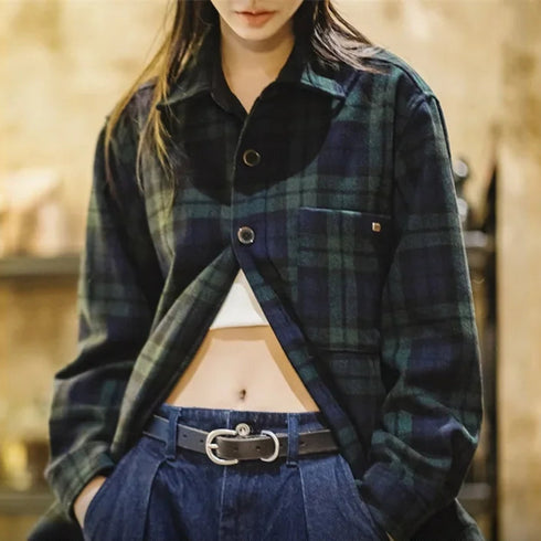 Person wearing a blue green plaid coat with a blurred background